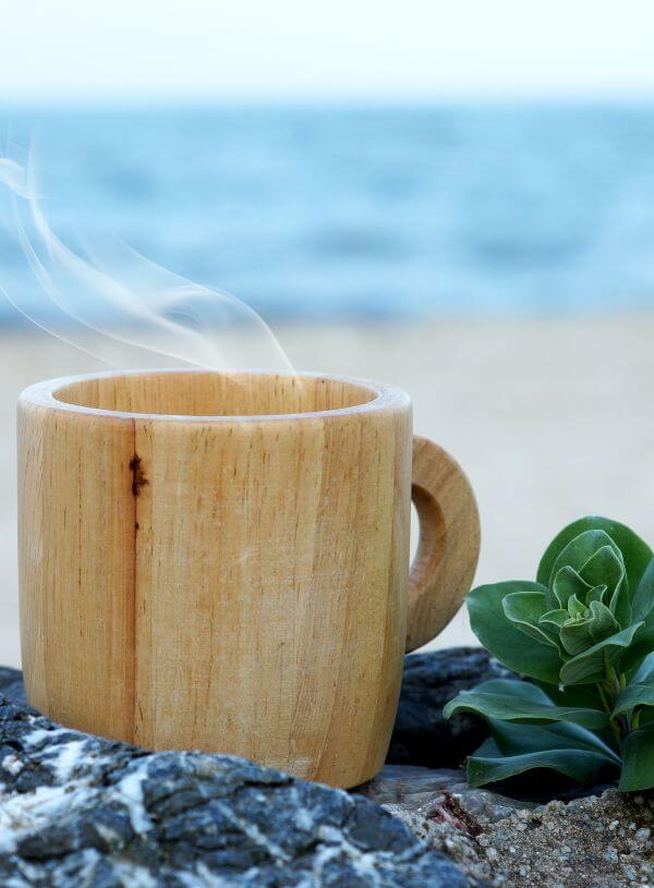 Coffee in a wooden mug on the beach